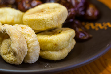 dried dates and figs in a ceramic plate on a wooden table