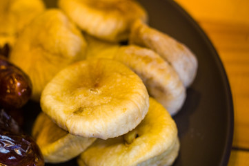 dried dates and figs in a ceramic plate on a wooden table