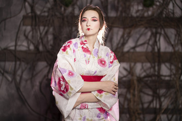 Fototapeta premium elegant girl in a classic traditional dress Japanese kimono white and pink standing alone on dark background in the studio
