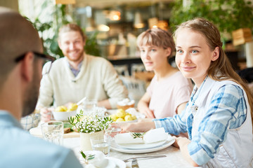Crop view of smiling young pretty woman spending time with friends in restaurant