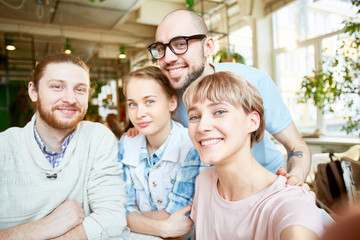 Happy company of friends taking selfie and looking at camera while meeting in cafe