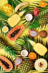 Plakaty  Egzotyczne owoce i liście palm tropikalnych na pastelowym żółtym tle - papaja, mango, ananas, banan, karambol, smoczy owoc, kiwi, cytryna, pomarańcza, melon, kokos, limonka. Widok z góry.