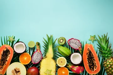 Tuinposter Exotic fruits and tropical palm leaves on pastel turquoise background - papaya, mango, pineapple, banana, carambola, dragon fruit, kiwi, lemon, orange, melon, coconut, lime. Top view. © jchizhe