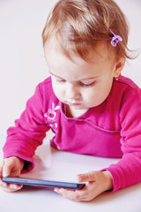 Little beautiful child girl using smartphone as symbol of work or study. Connect to the Internet with smartphone. (Development, education, technology concept)