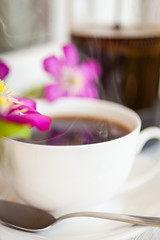 Cup of black coffee and pink blooming flowers  