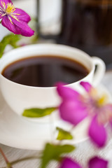 Cup of black coffee and pink blooming flowers  