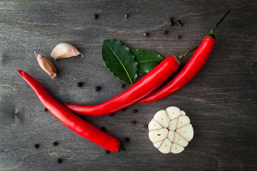 Red chili peppers, garlic, bay leaf, rosemary and various spices on black wood  background