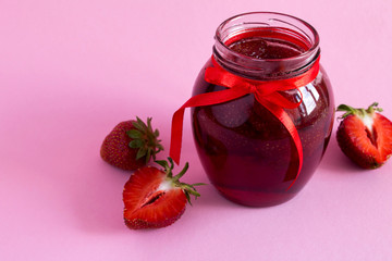 Strawberry  jam in the glass jar on the pink  background