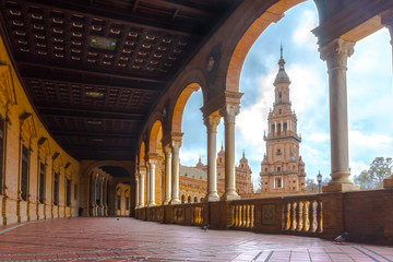 Famous Plaza de Espana hallway in Seville, Spain. Filled in a soft light with the tower in the background. Pigeons walking by with no one else around.