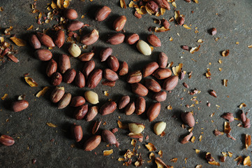 Peanuts are scattered on a dark braun background.