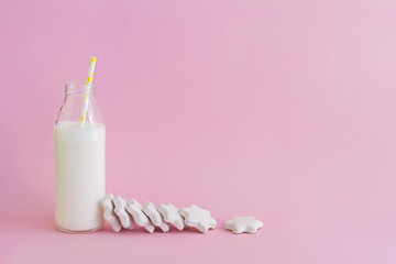 Fototapeta na wymiar Bottle of milk and cookies shaped stars on pink background