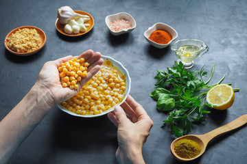 Ingredients for hummus on the black kitchen table. Chickpeas in hand.