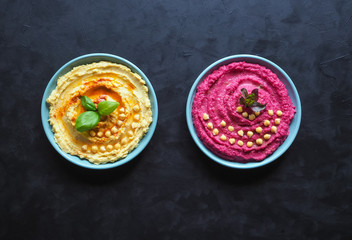 Two plates of hummus on a black kitchen table.