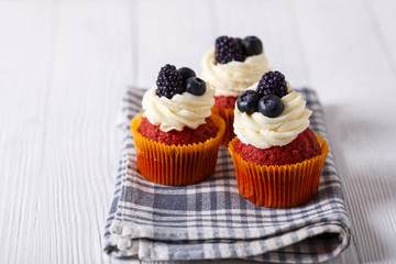 Tasty red velvet cupcakes on wooden table. Geyser coffee maker.