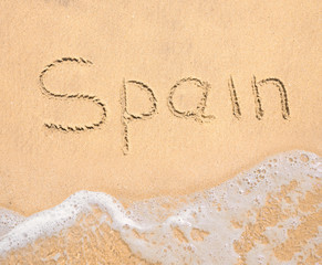 The word Spain written in the sand on beach