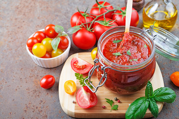 Tomato sauce in a glass jar and ingredients.
