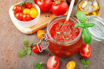 Tomato sauce in a glass jar and ingredients.