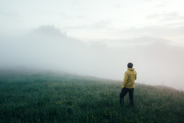 Fototapeta na wymiar Alone tourist in yellow jacket meets the dawn on high mountains.