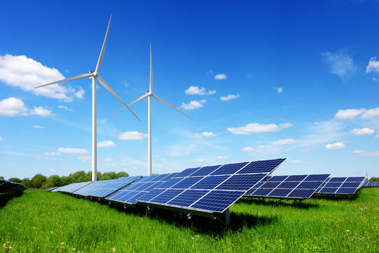 Solar panel on blue sky background. Green grass and cloudy sky. Alternative energy concept