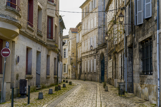 View of a cobblestone street with old buildings in Angouleme, France. The buildings look worn but dreamy and beautiful.