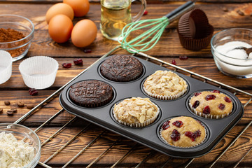 Different Muffins in bakeware or muffin pan on broun wooden background. Basic muffin recipe. Homemade muffins for breakfast or dessert.