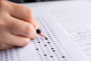 Fototapeta premium Students hand holding pencil writing selected choice on answer sheets and Mathematics question sheets. students testing doing examination. school exam