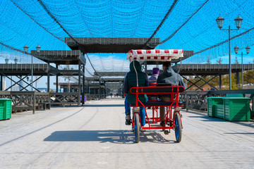 Naklejka premium The family rides a four-Wheeler on a bike path on the waterfront in the city of Kazan. summer vacation, travel