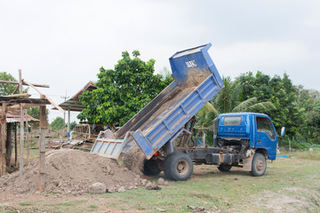 Obraz premium Blue dump truck unloading soil at construction site