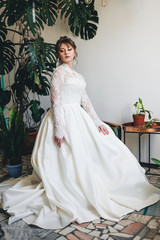 Fototapeta premium pretty woman in a wedding dress in the depressions of living plants.