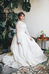 Fototapeta premium pretty woman in a wedding dress in the depressions of living plants.