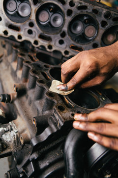 Mechanic fixing an engine for a head gasket repair in a garage.