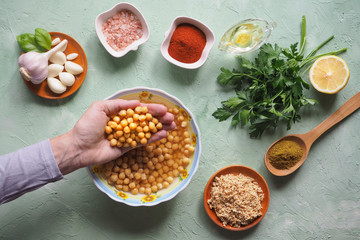 Chickpeas in hand. Ingredients for traditional hummus on the kitchen table.