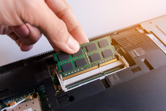 Technician installing RAM stick (random access memory) to socket on laptop