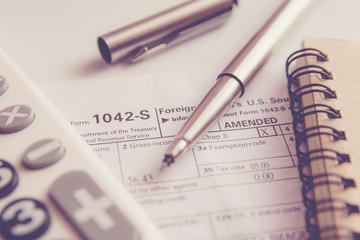 US tax form with pen and calculator selective focus / taxation concept