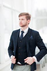 pensive newcomer businessman in a business suit stands near a wi