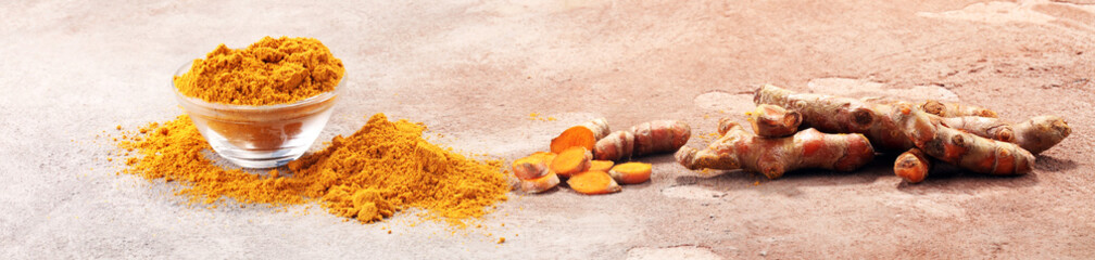 Turmeric powder and fresh turmeric on grey background