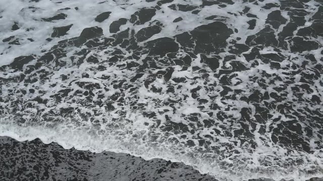 Waves on the shoreline of a black sand beach in Taranaki New Zealand