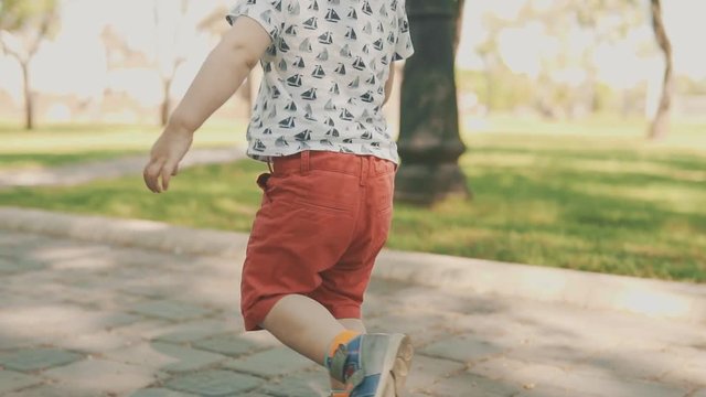 Little boy in shorts and hat running outside. Slow motion of child running in park