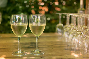 Two glasses of cold white wine on a wooden table in the nature