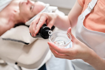Female hands of a beautician with a brown bottle. Cosmetic procedure