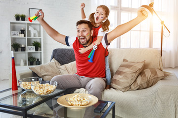 family of fans watching a football match on TV at home