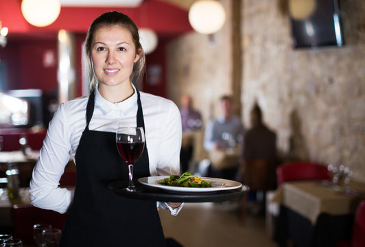 Portrait of smiling young waitress with serving tray