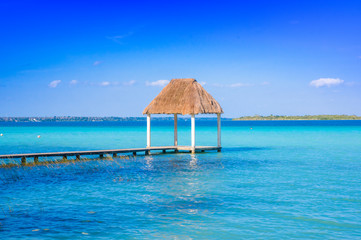 Color graded picture of a pier with clouds and blue water at the Laguna Bacalar, Chetumal, Quintana Roo, Mexico