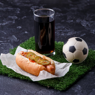 Photo of glass of beer, green grass with soccer ball, hotdog