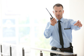 Male security guard using portable radio transmitter indoors