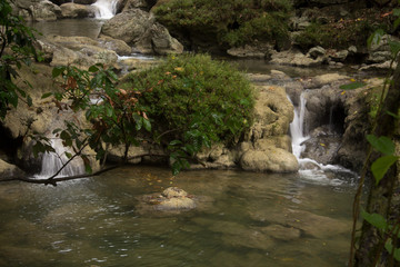 Fototapeta na wymiar Río con varias cascadas pequeñas, rocas y arbustos