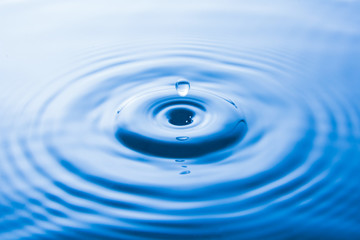 Water drop falling into water make waves. Water splash or water drop background.