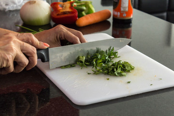 Mujer picando alimentos en una tabla de picar blanca de acrilico