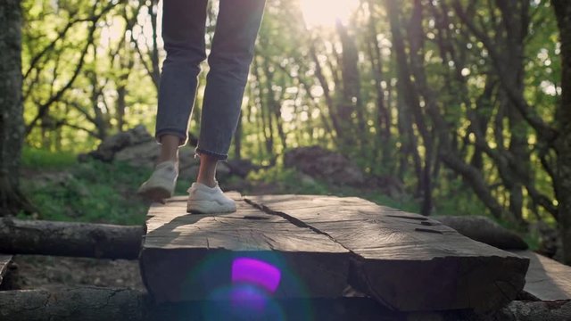 Cropped picture of young woman in sneaker dancing on big log in forest, under sunshine slow motion. Human and nature