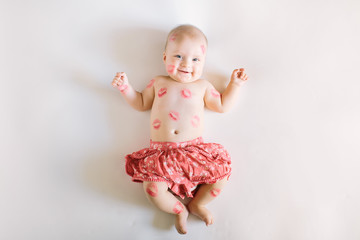 Image of adorable child with red kisses on the skin, happy baby girl isolated on white background,...